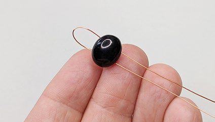Black bead with folded wire threaded through it.